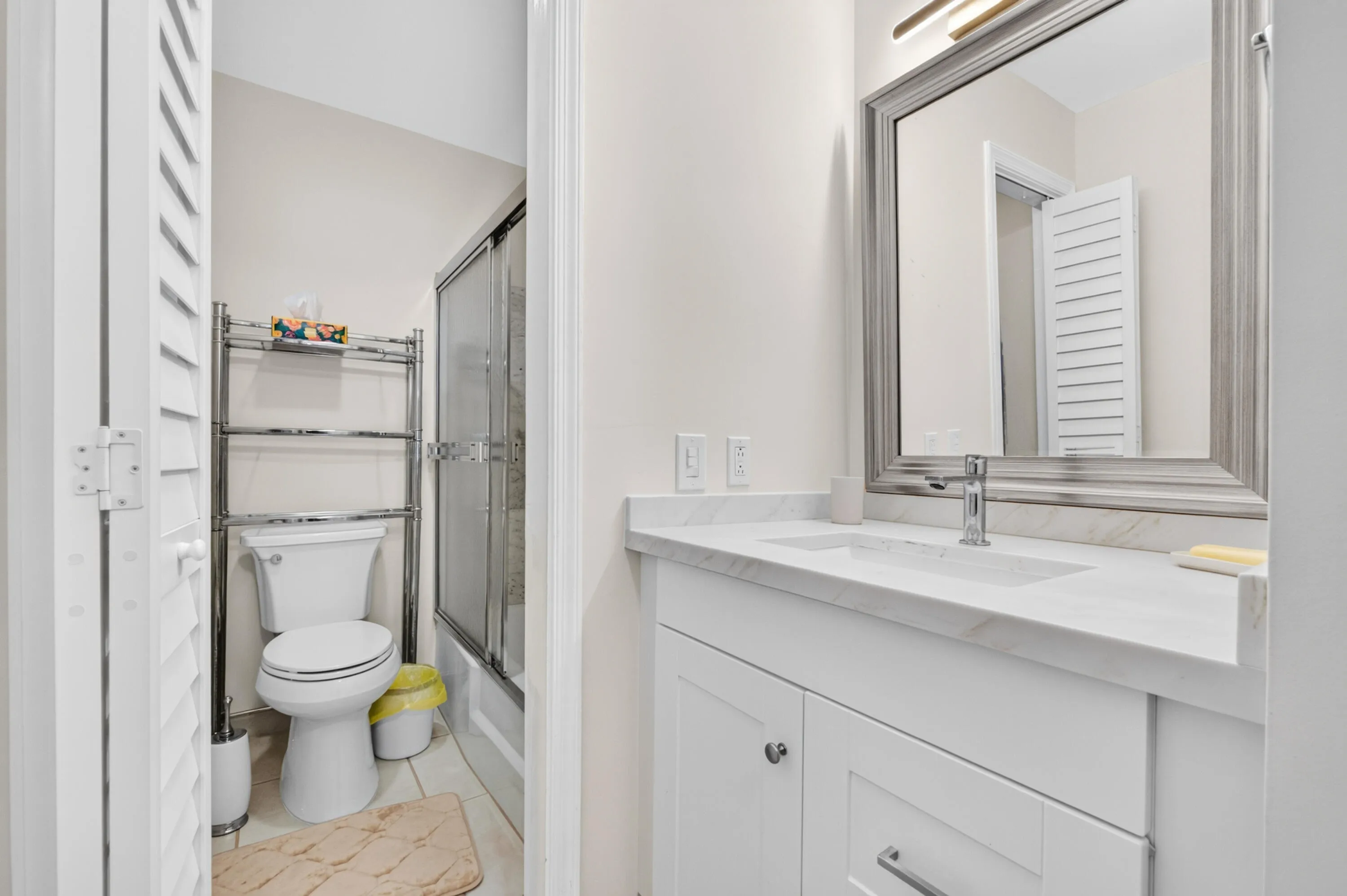 White shaker vanity with chrome hardware, an undermount sink, and a light-toned countertop