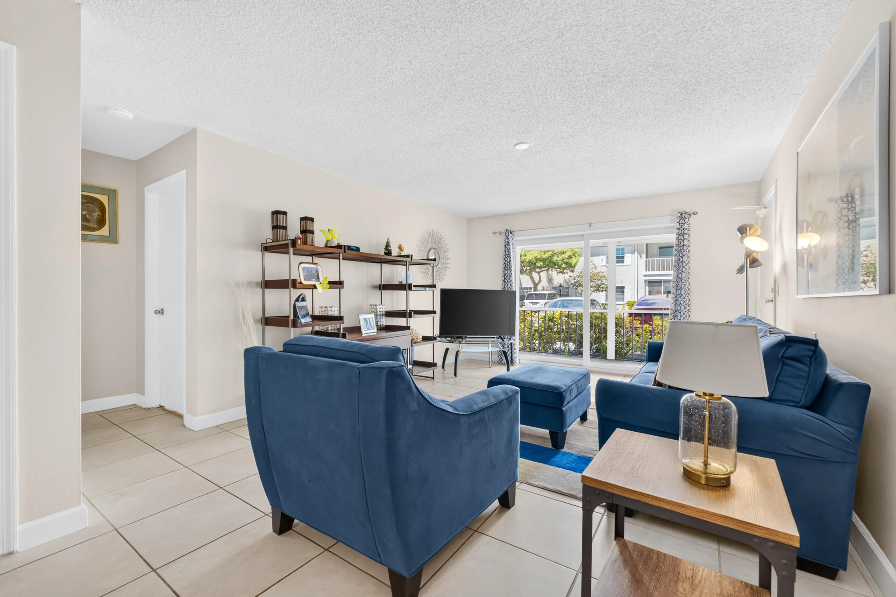 Bright and spacious living area featuring tile flooring, recessed lighting, and large windows with plantation shutters