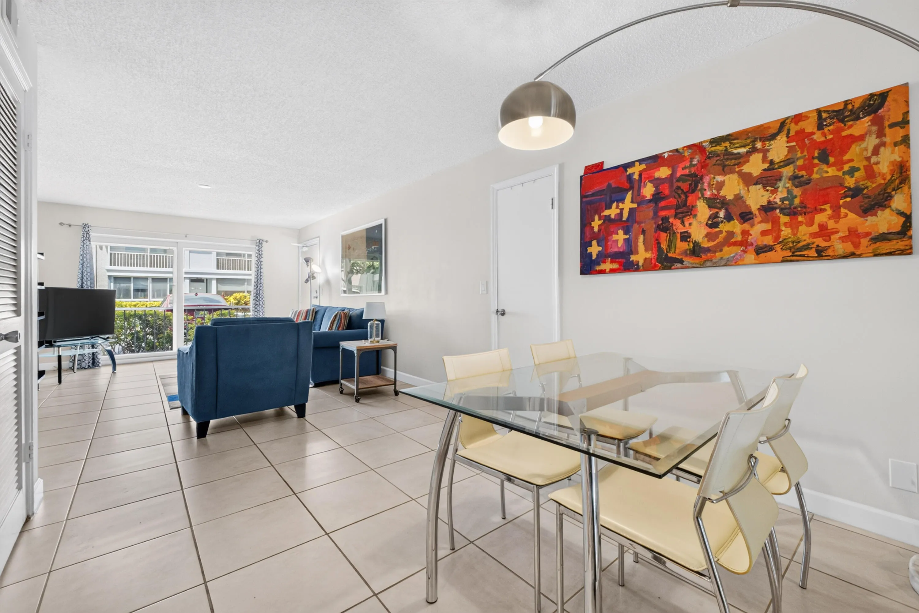 Open concept living and dining area with tile flooring throughout, white walls, and a sliding glass door