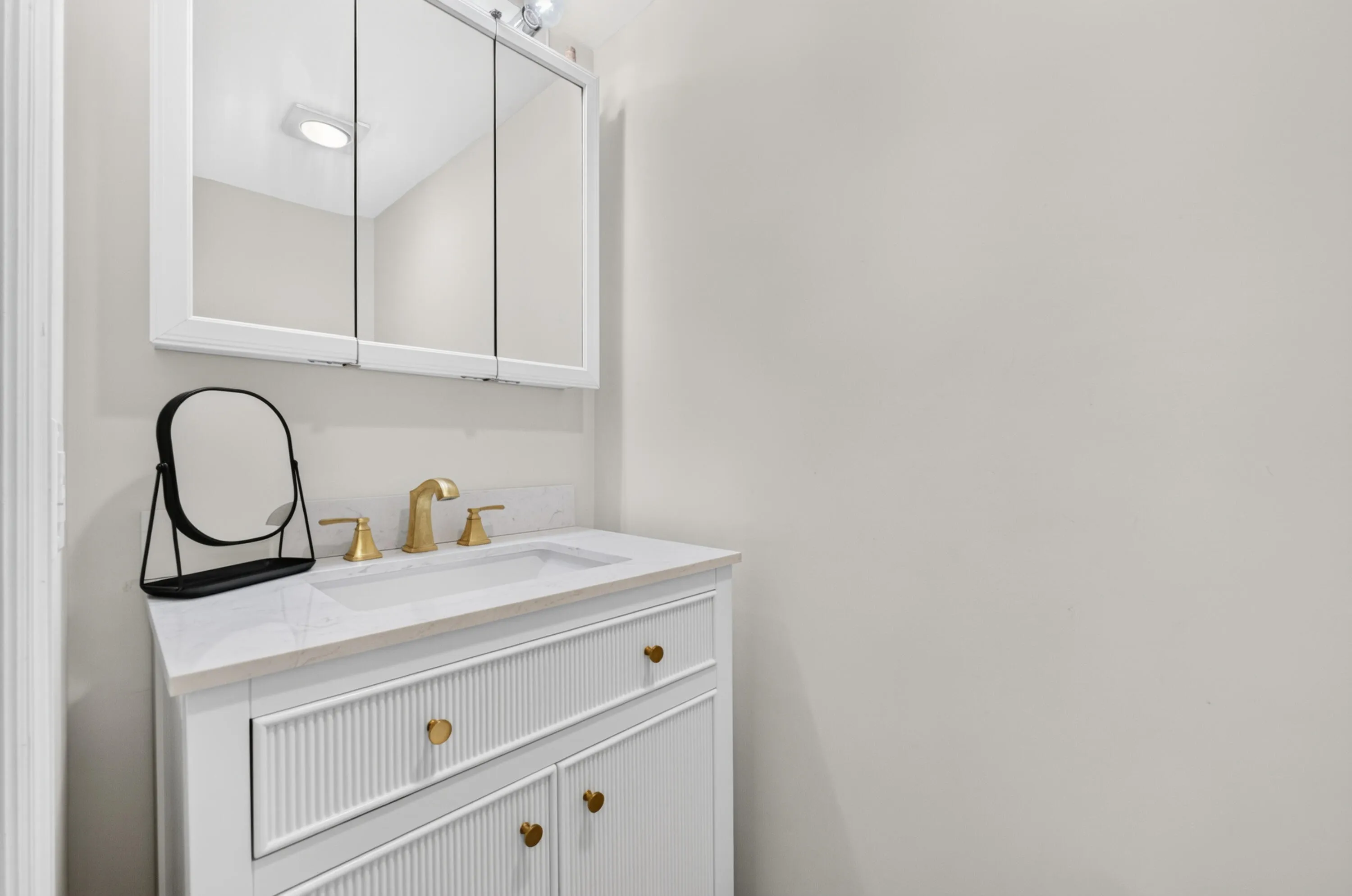 White vanity with gold-tone hardware, undermount sink, and polished countertop