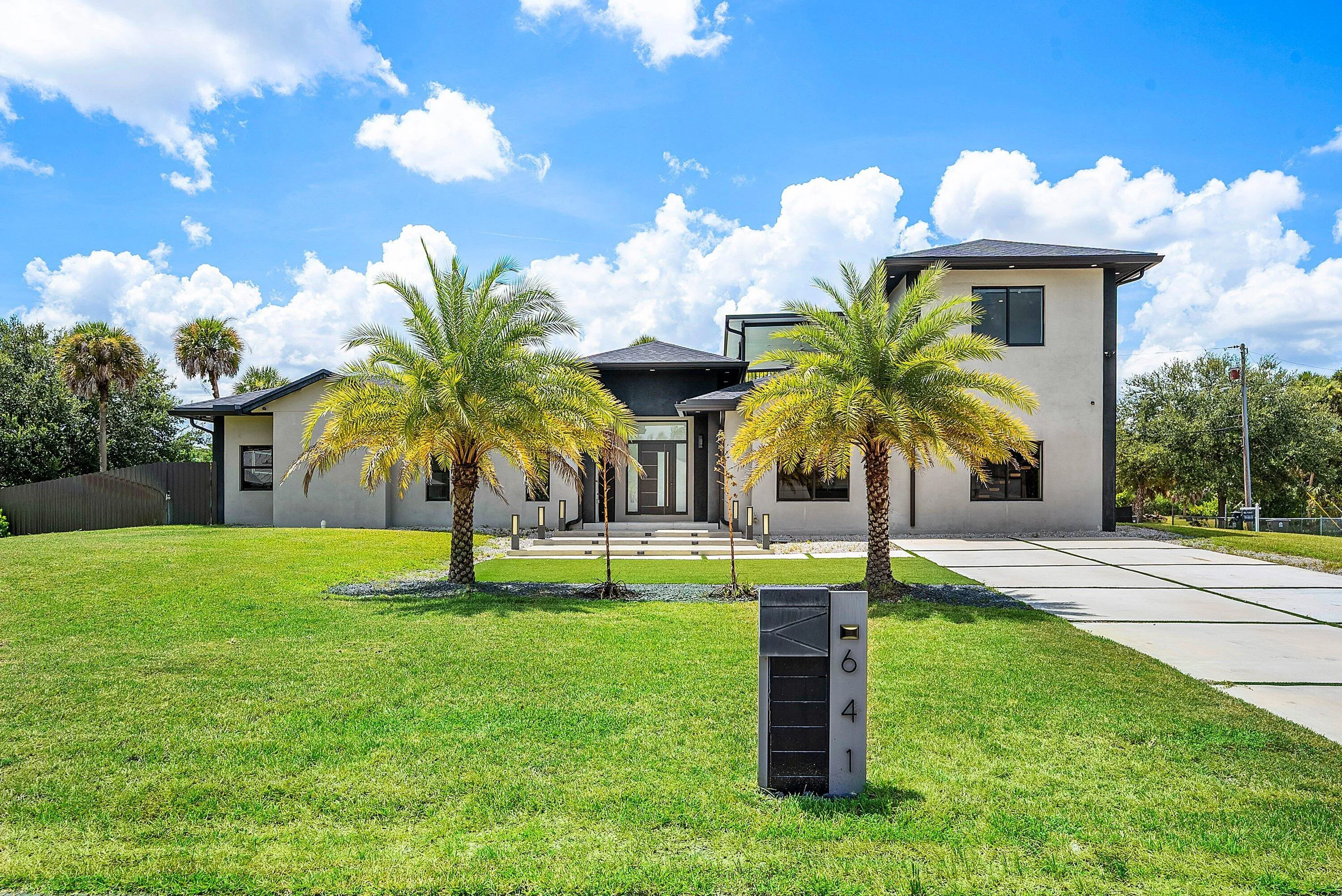 Contemporary exterior with a flat roofline, stucco finish, large windows, and a modern concrete driveway