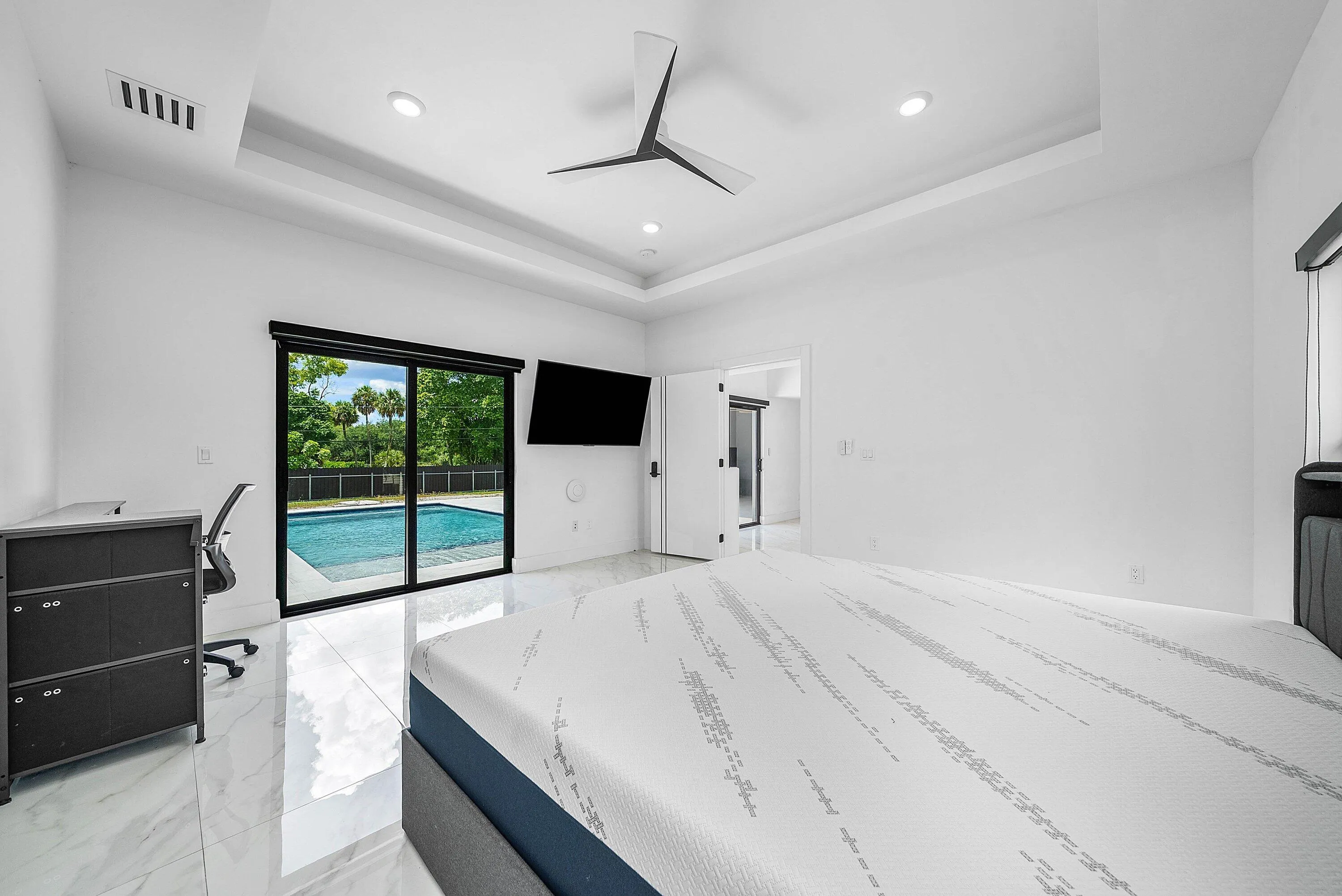 Recessed lighting, modern ceiling fan, tray ceiling, sliding glass doors, and polished tile flooring