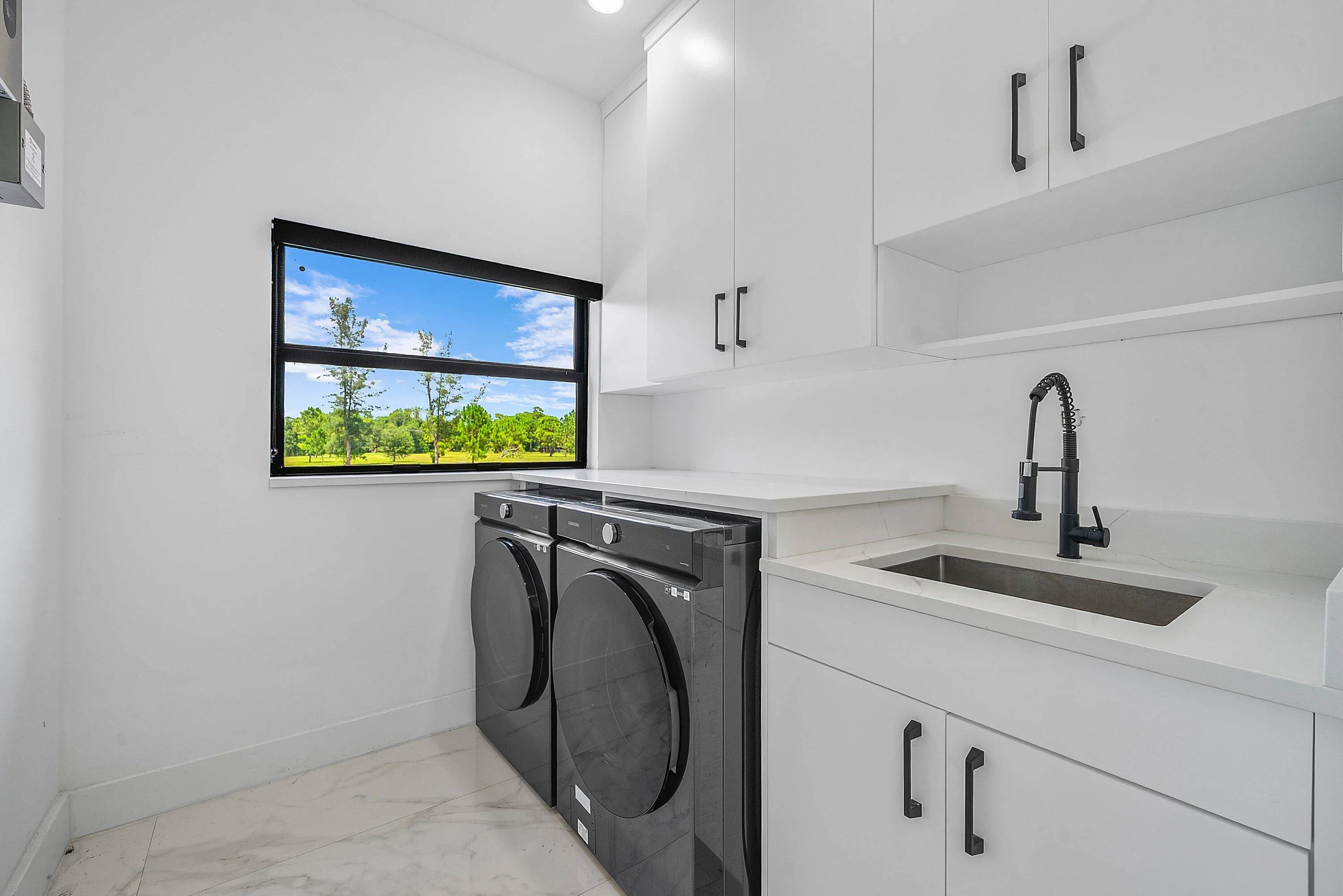 White cabinetry with black hardware, stone countertops, undermount sink with a matte black faucet, and white tile flooring