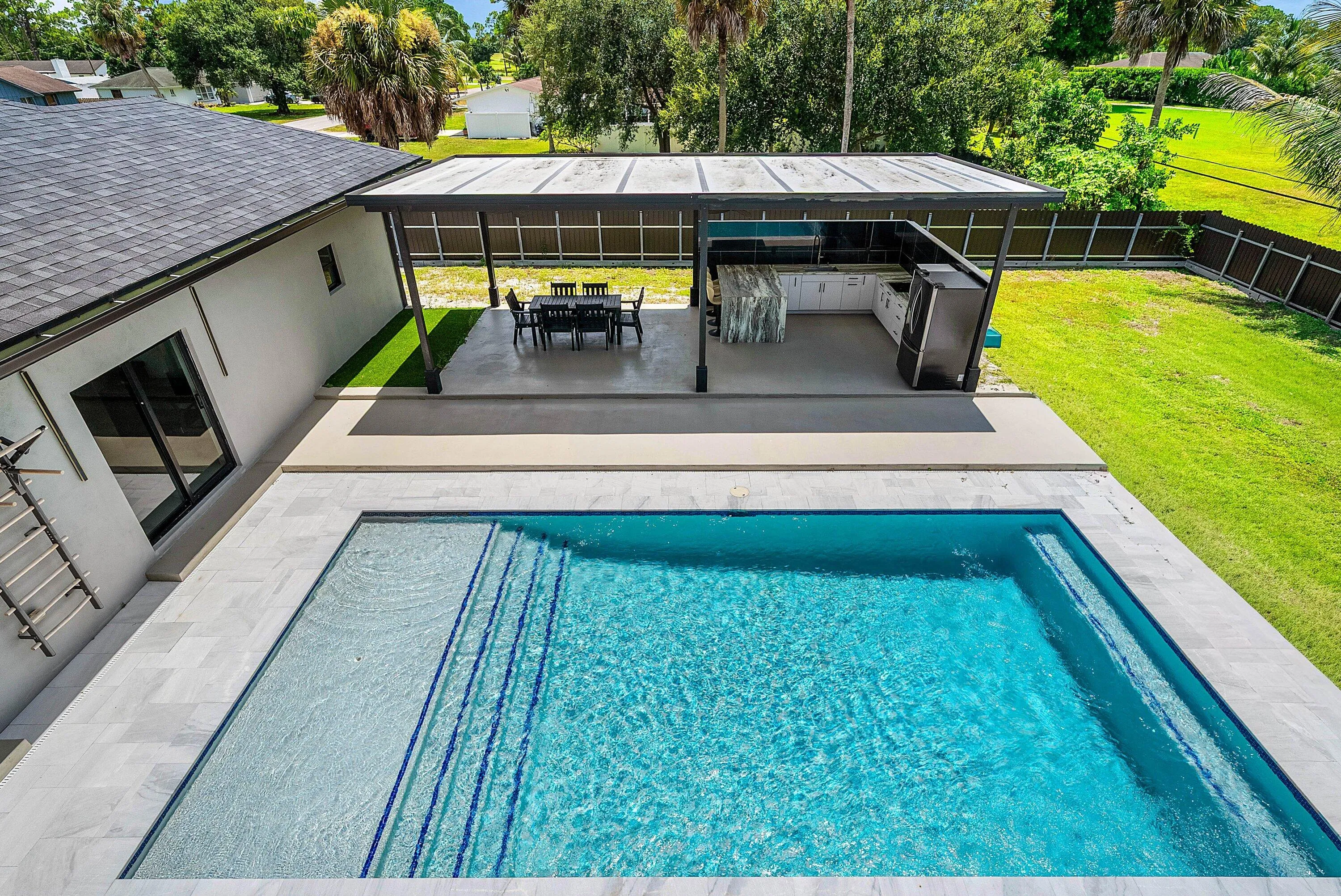 Rectangular swimming pool with integrated steps, surrounded by light-toned tile decking
