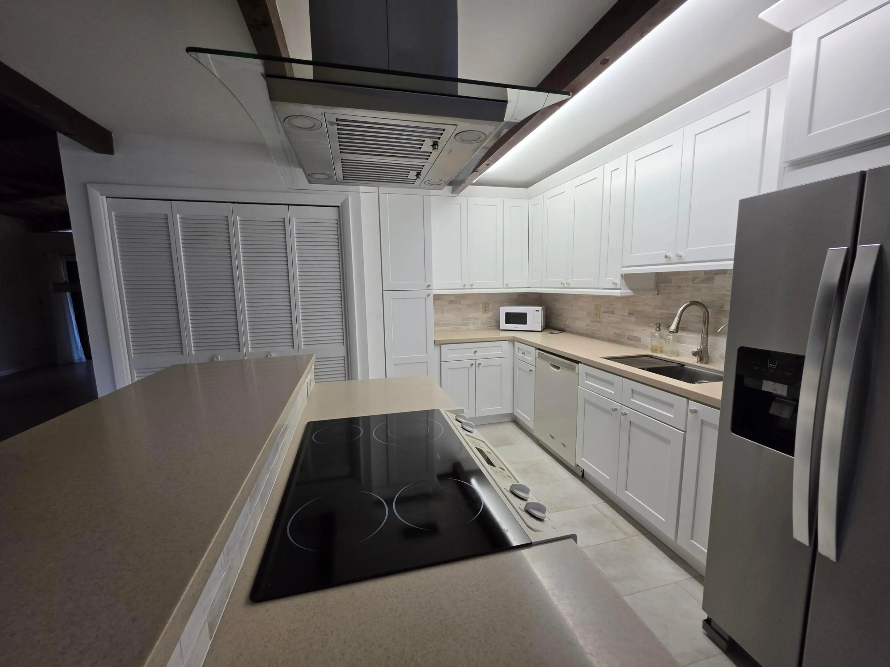 THE GLASS COOKTOP, DESIGNER VENT AND STAINLESS FRIDGE ADD TO THE SOPHISTICATED FEEL OF THIS SPACE.