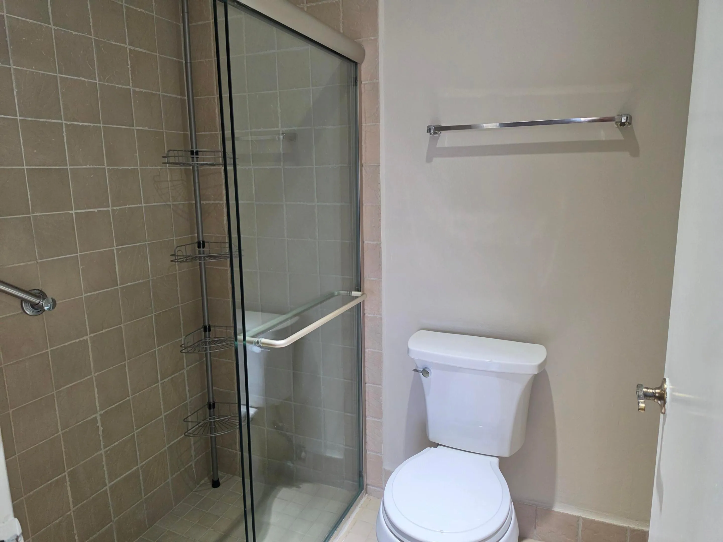 THE PRIMARY BATH INCLUDES A SEPARATE SHOWER ENCLOSURE WITH FLOOR TO CEILING TILE AND NEUTRAL PALETTE.