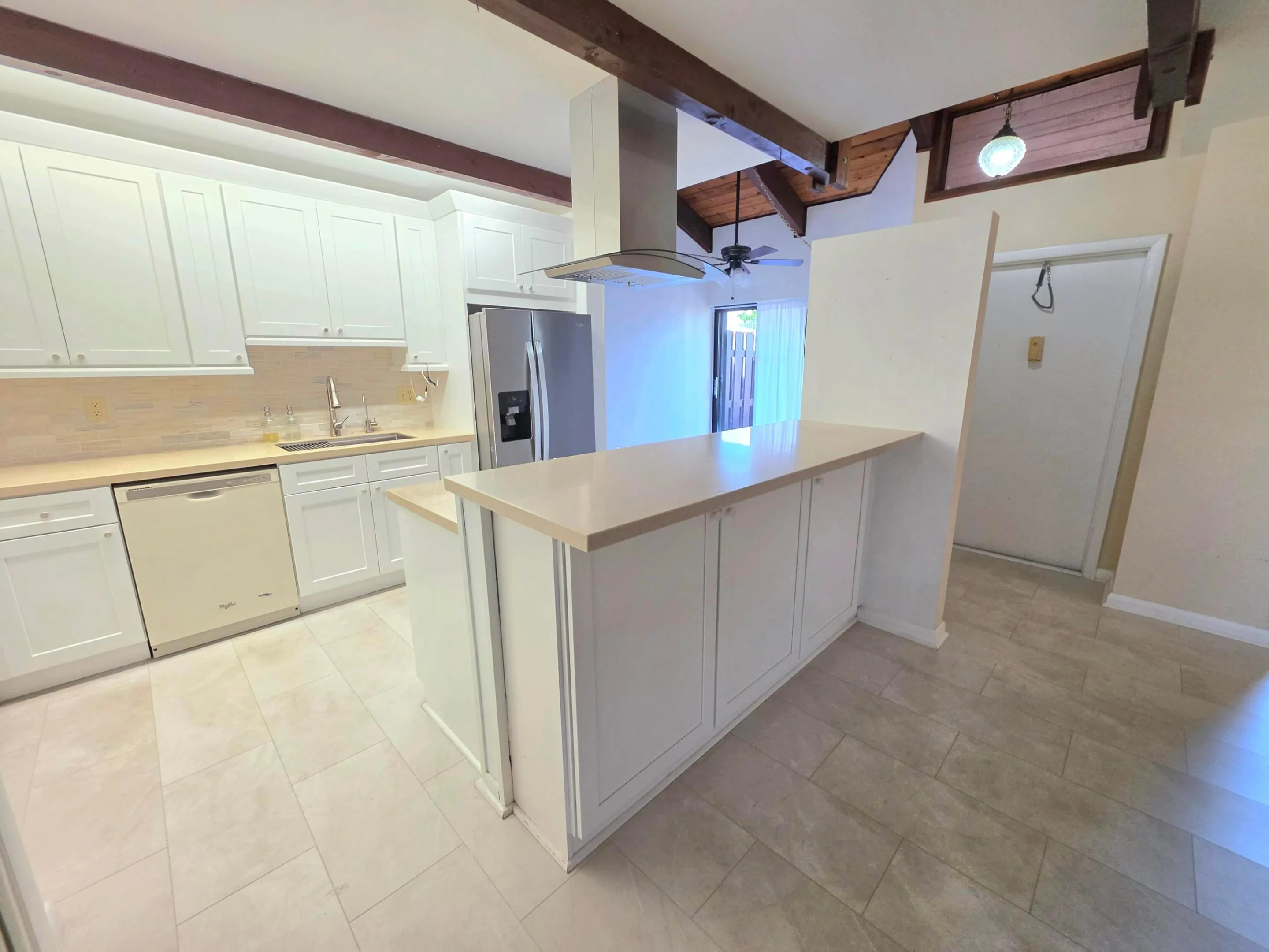 RENOVATED KITCHEN ENJOYS WHITE SHAKER CABINETS, BREAKFAST BAR, NEW COUNTERS, DESIGNER VENT HOOD, STAINLESS FRIDGE AND NEW FLOORING.
