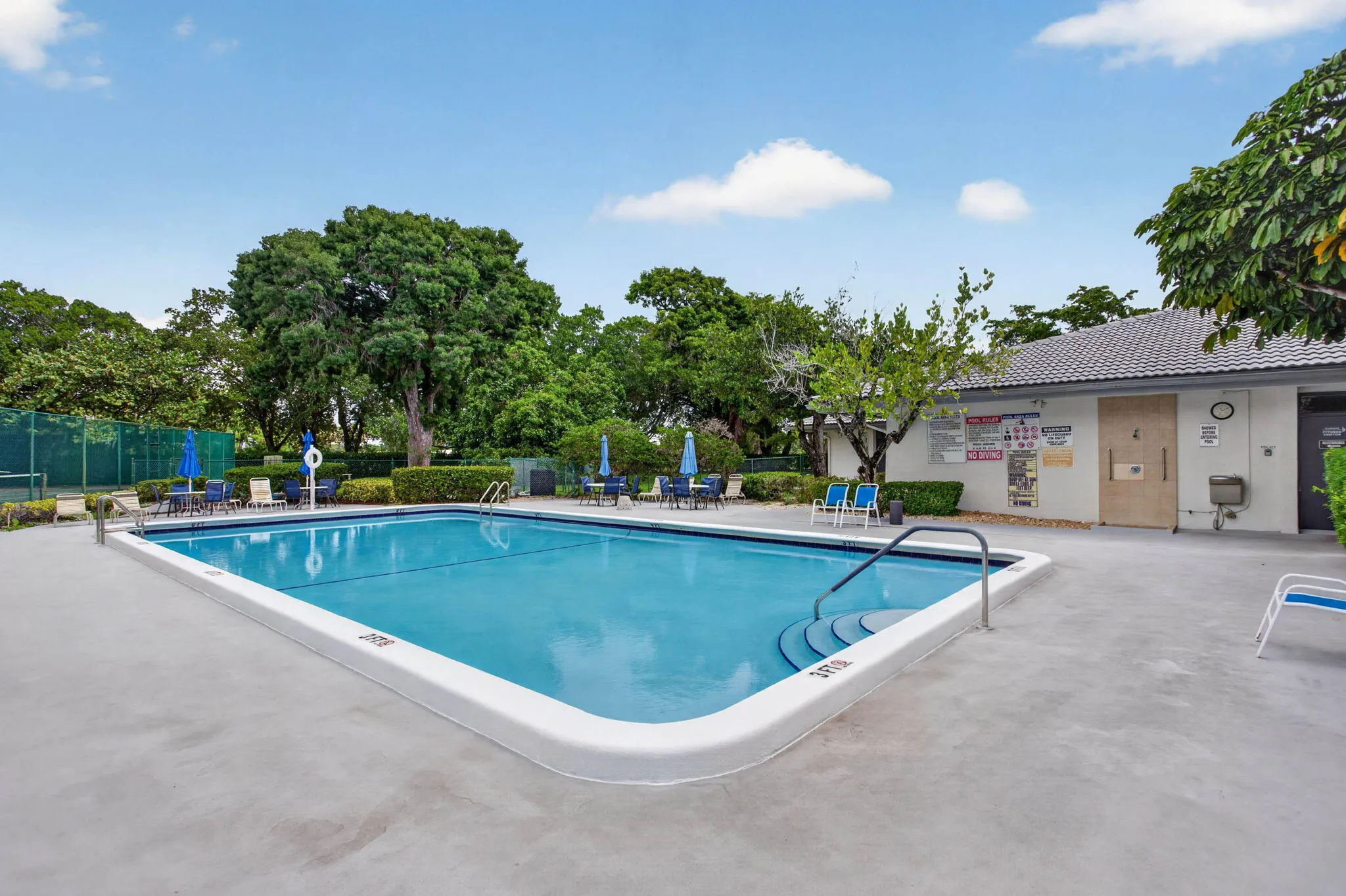 Rectangular swimming pool with integrated steps and handrail, surrounded by a concrete pool deck