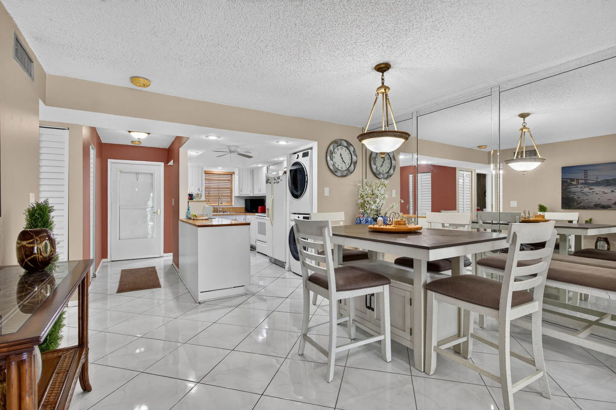 White tile flooring, ceiling-mounted light fixtures, white kitchen cabinetry, and a stacked washer and dryer