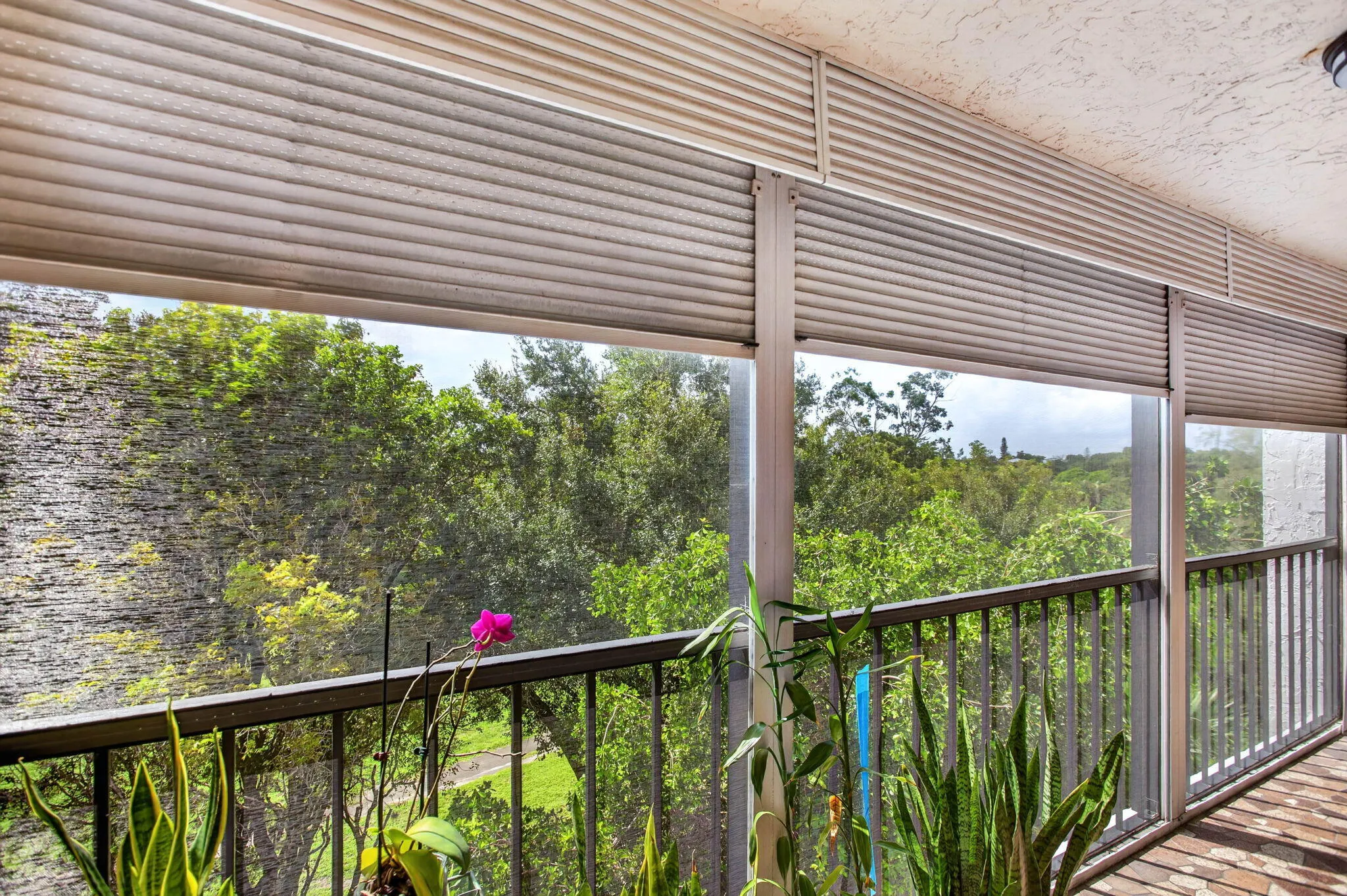 Enclosed balcony with roll down shutters and a metal railing