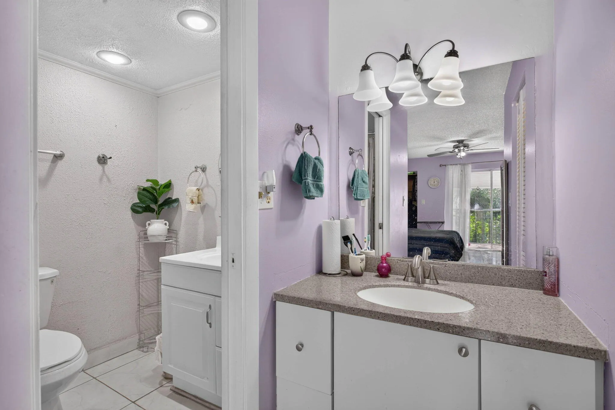 Dual vanity areas with integrated sink, stone-finish countertop, and white cabinetry