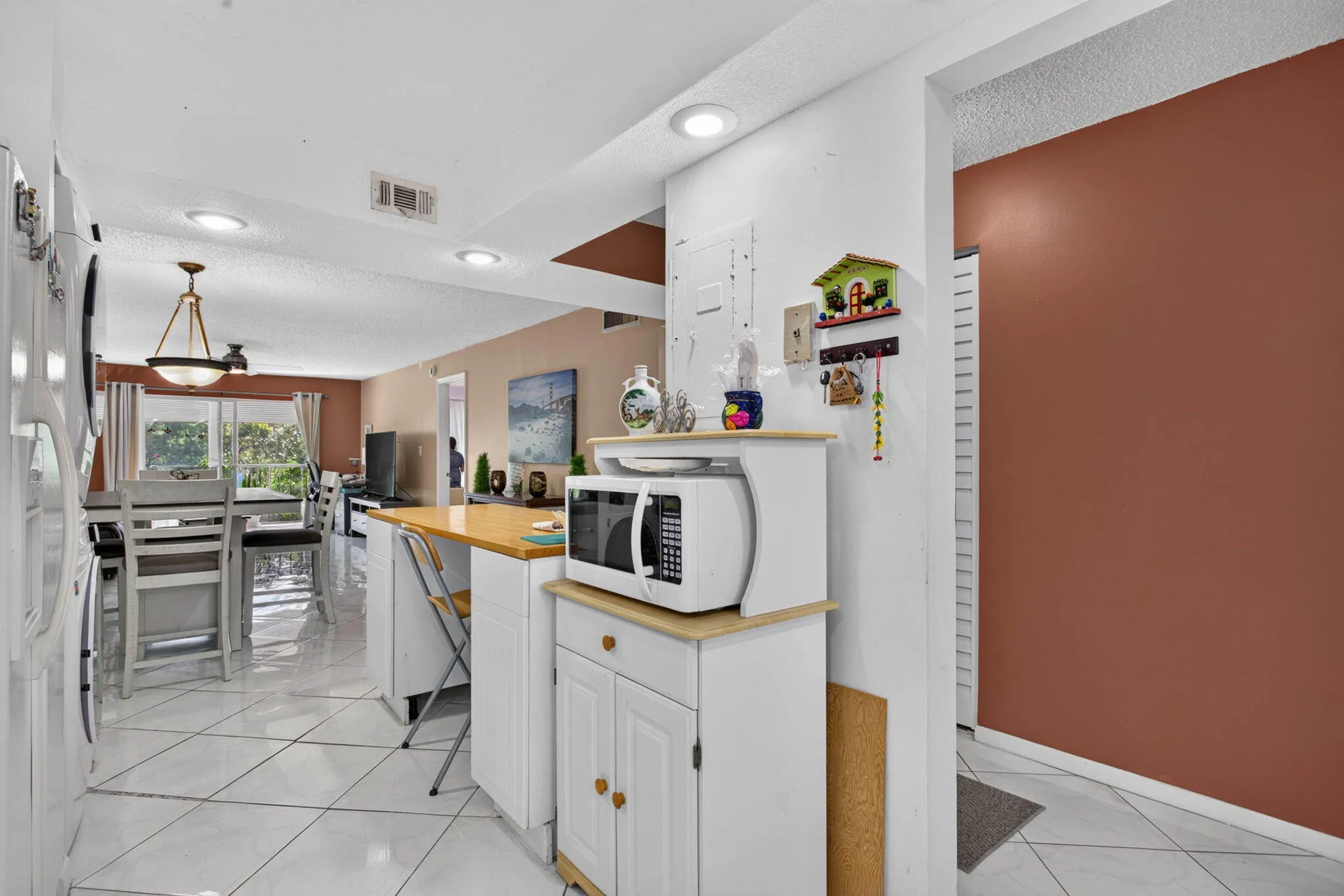 White tile flooring, recessed lighting, and a built-in kitchen island with a wood-finish countertop