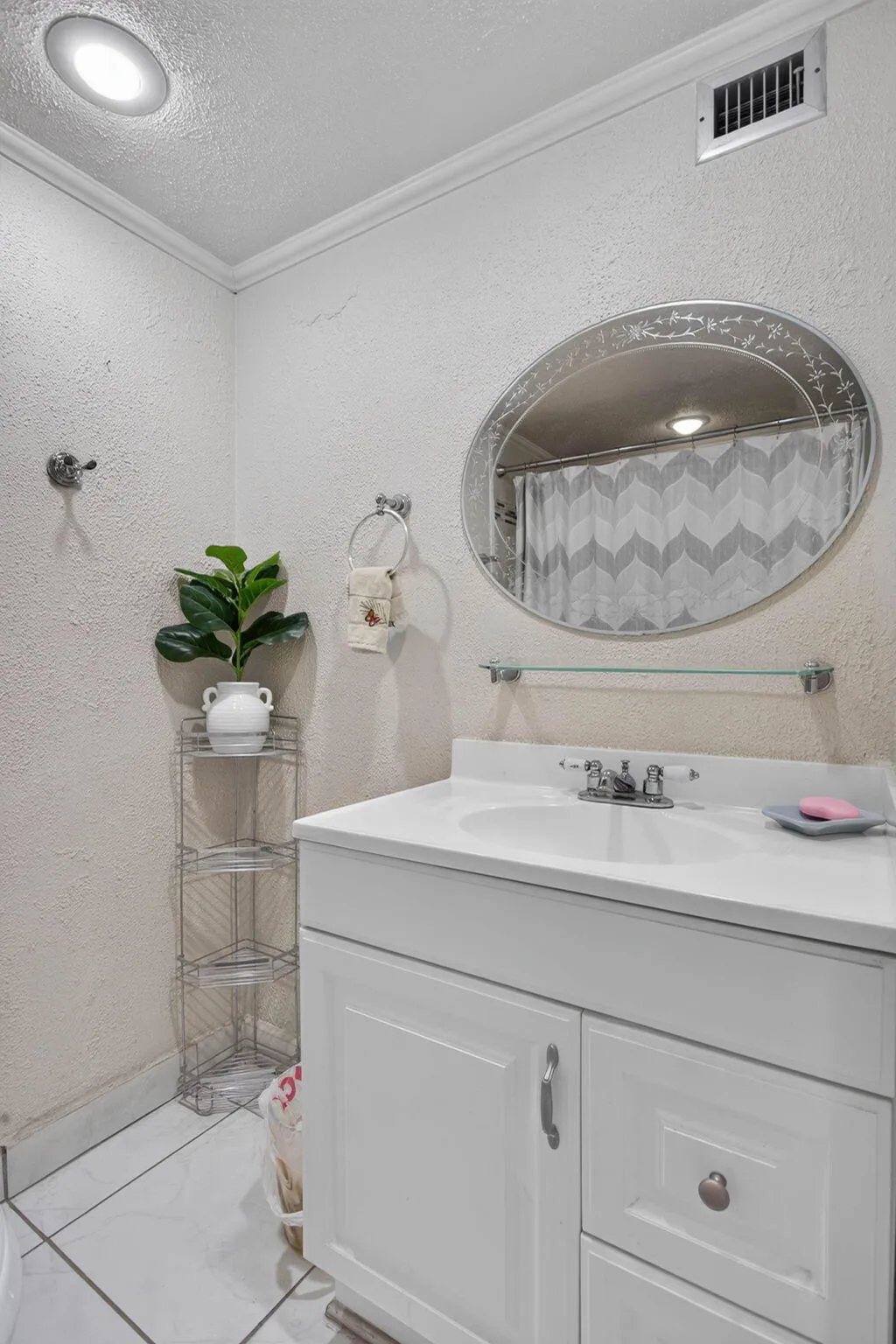 White vanity with an integrated sink, polished chrome faucet, and decorative oval mirror