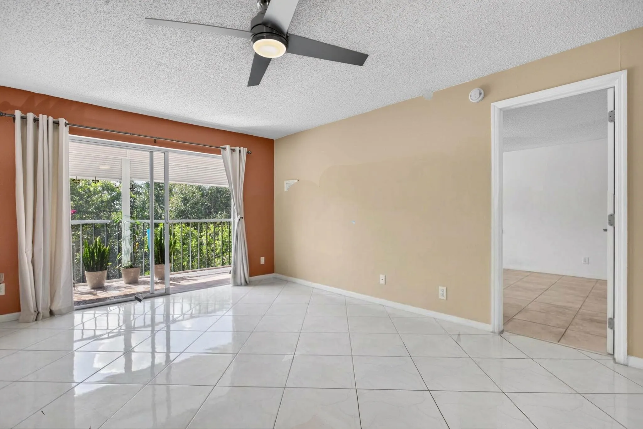 White tile flooring, sliding glass door to a balcony, ceiling fan, and painted walls
