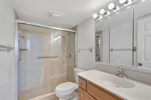 Glass-enclosed shower, built-in vanity with integrated sink, wood-finish cabinetry, and mirrored medicine cabinet