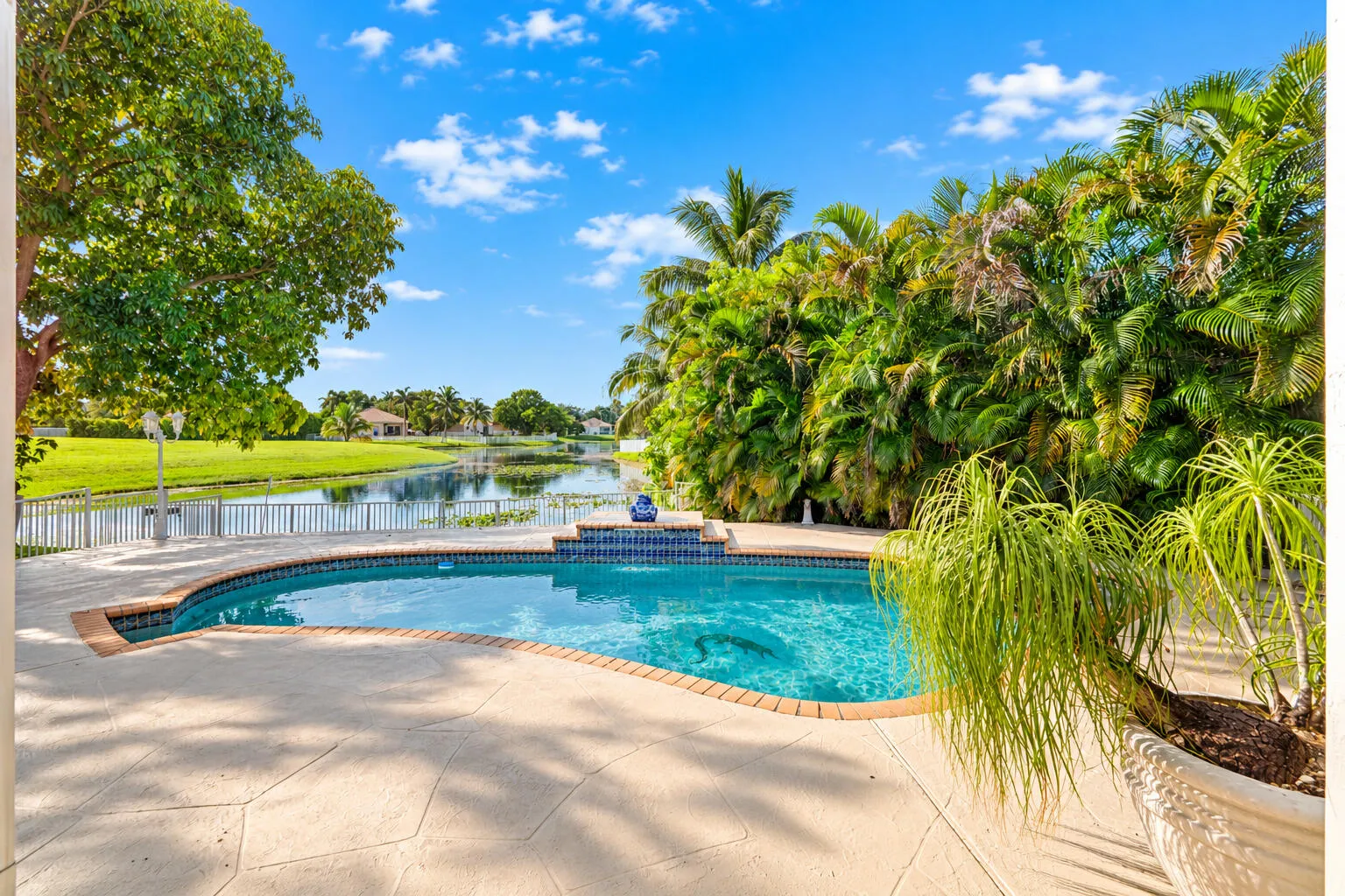 Private pool is framed by tropical landscaping with an open lake view beyond.