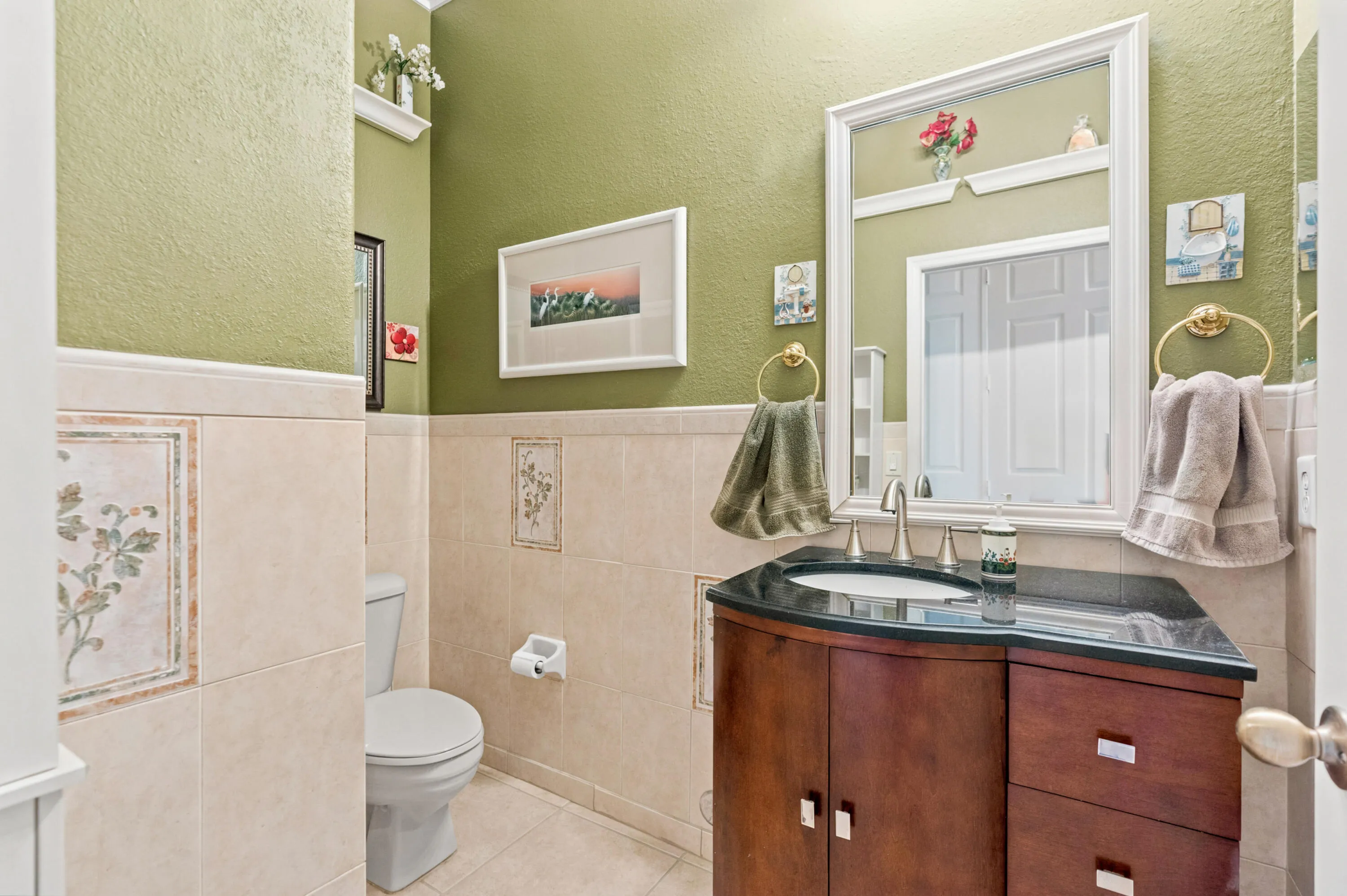 Half bathroom features a granite countertop vanity, tiled walls and warm finishes.