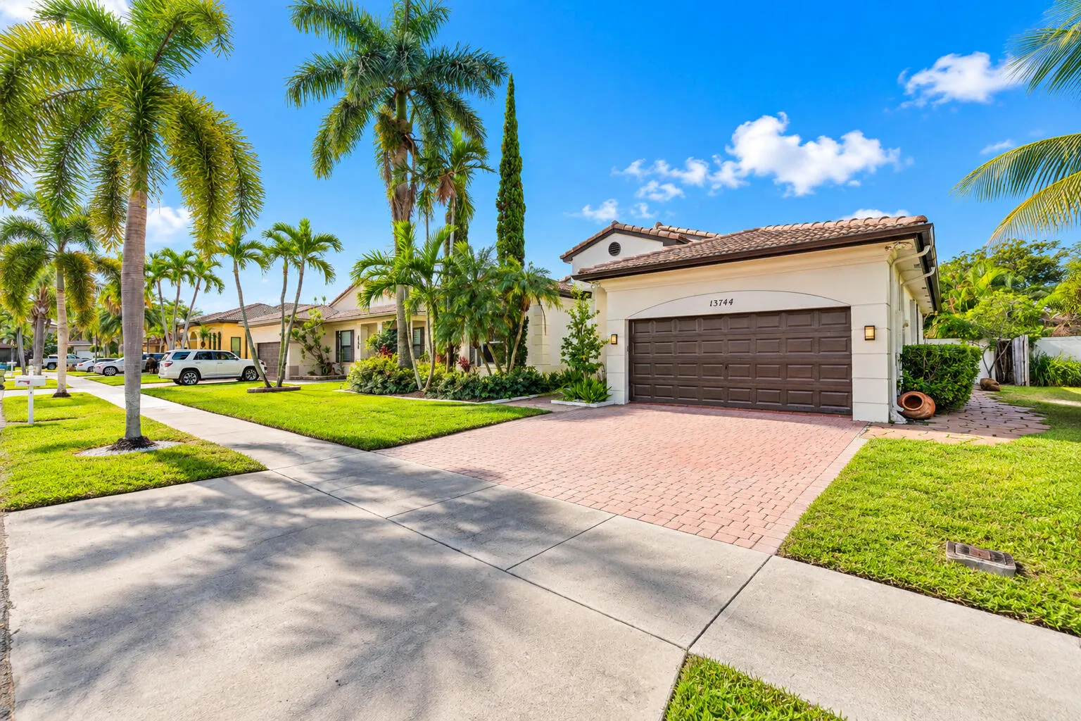 Exterior view highlights the home’s attractive entry, lush landscaping and brick-paver driveway.