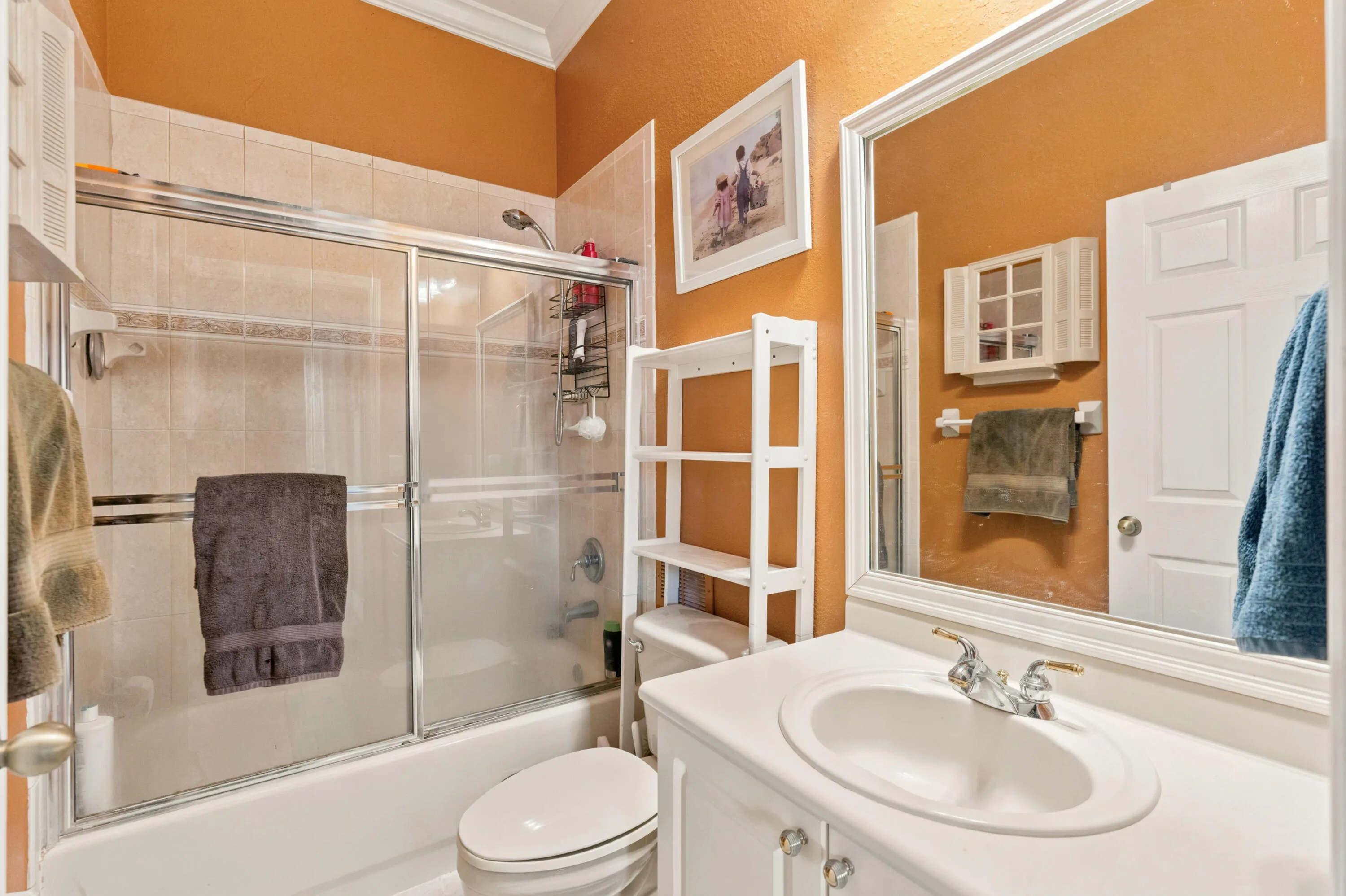 Full bathroom features a tub-shower combination, vanity and tiled surround.