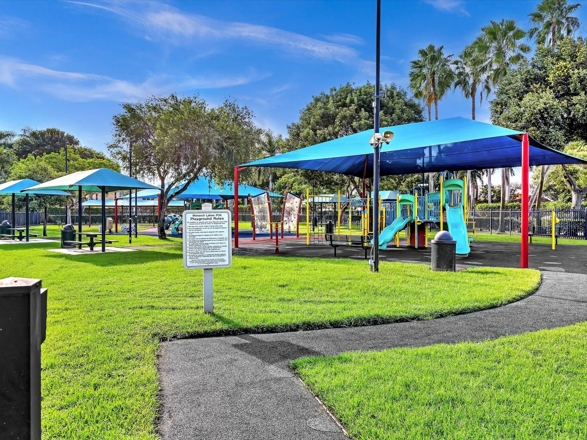 Community playground and park with shaded play structures, open lawn and seating areas.