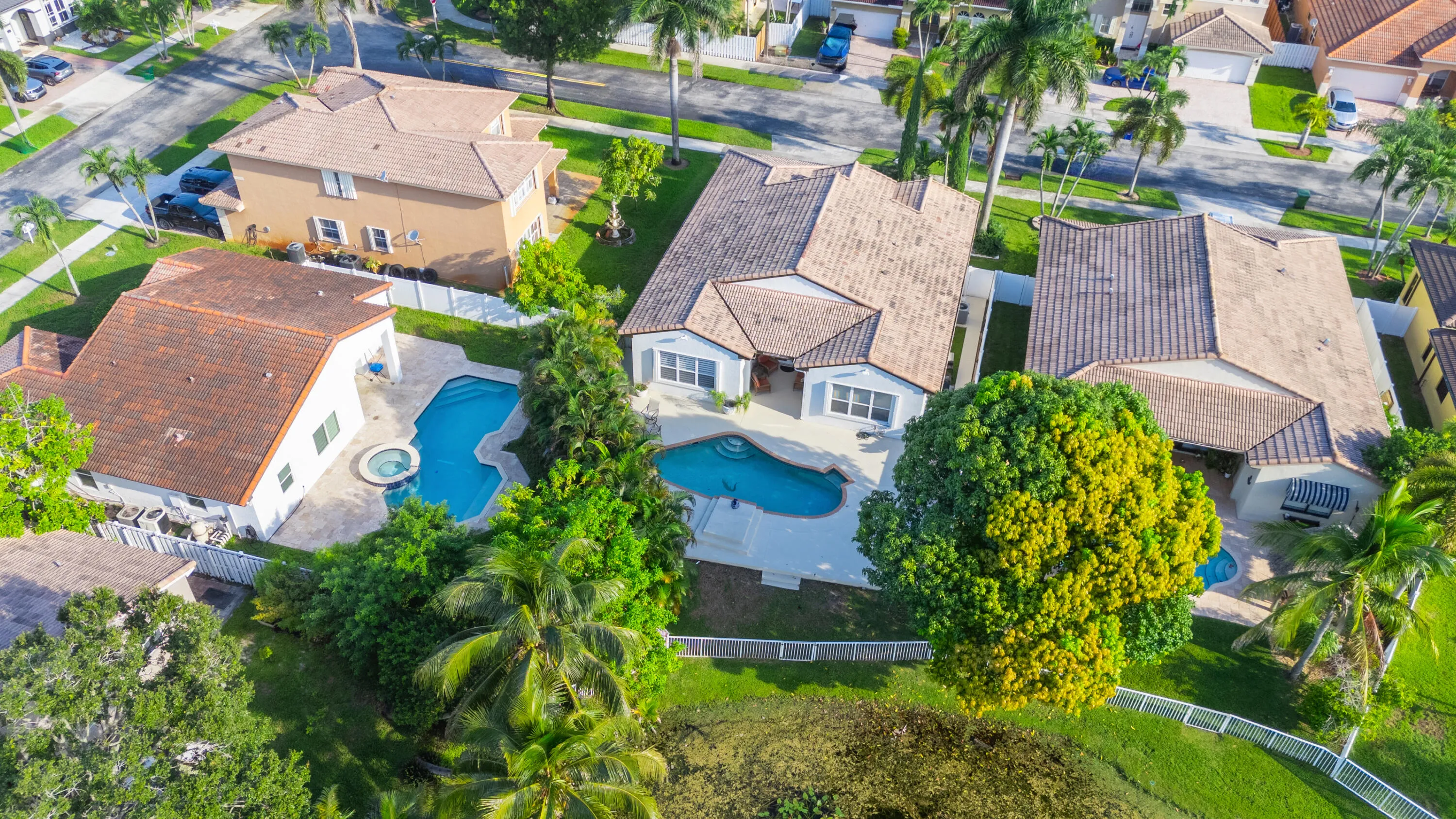Aerial perspective showcases the home’s backyard layout with private pool and water just beyond the property.