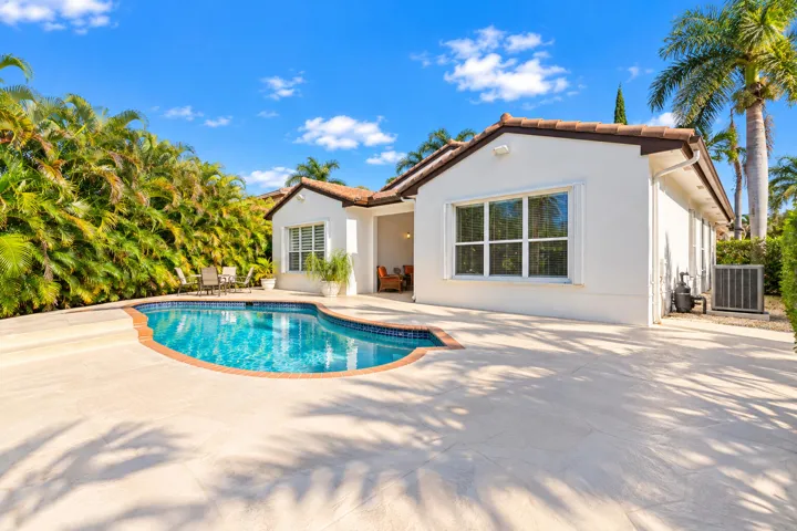 Another perspective captures the pool, generous surrounding patio and tropical landscaping along the property.