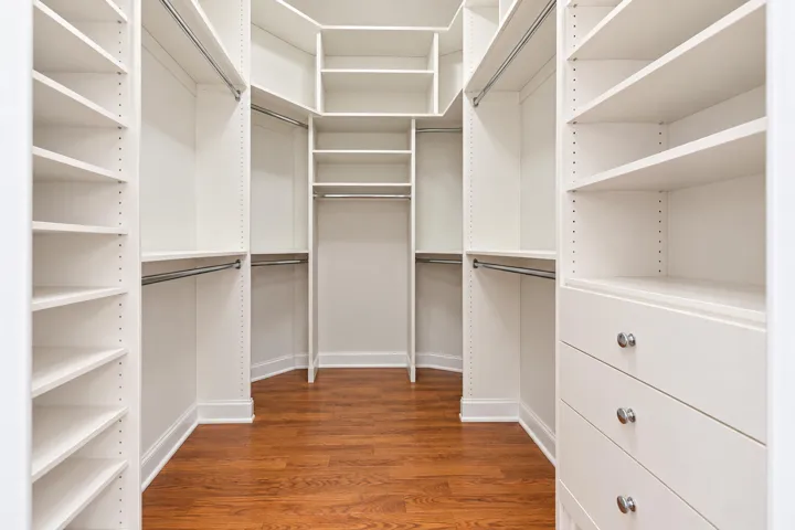 Walk-in closet features extensive built-in shelving, hanging space and drawer storage.