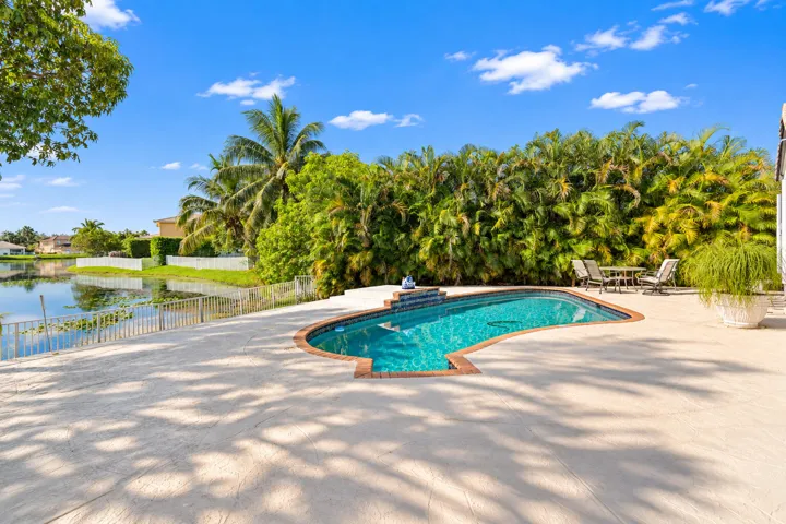 Wide pool deck opens toward the lake, combining outdoor living space with a peaceful waterfront backdrop.