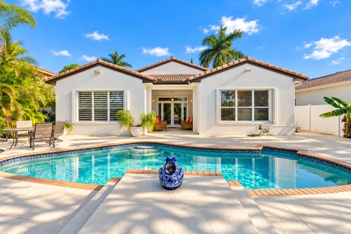 Rear exterior showcases the home’s covered patio, expansive pool deck and direct connection to the outdoor living area.