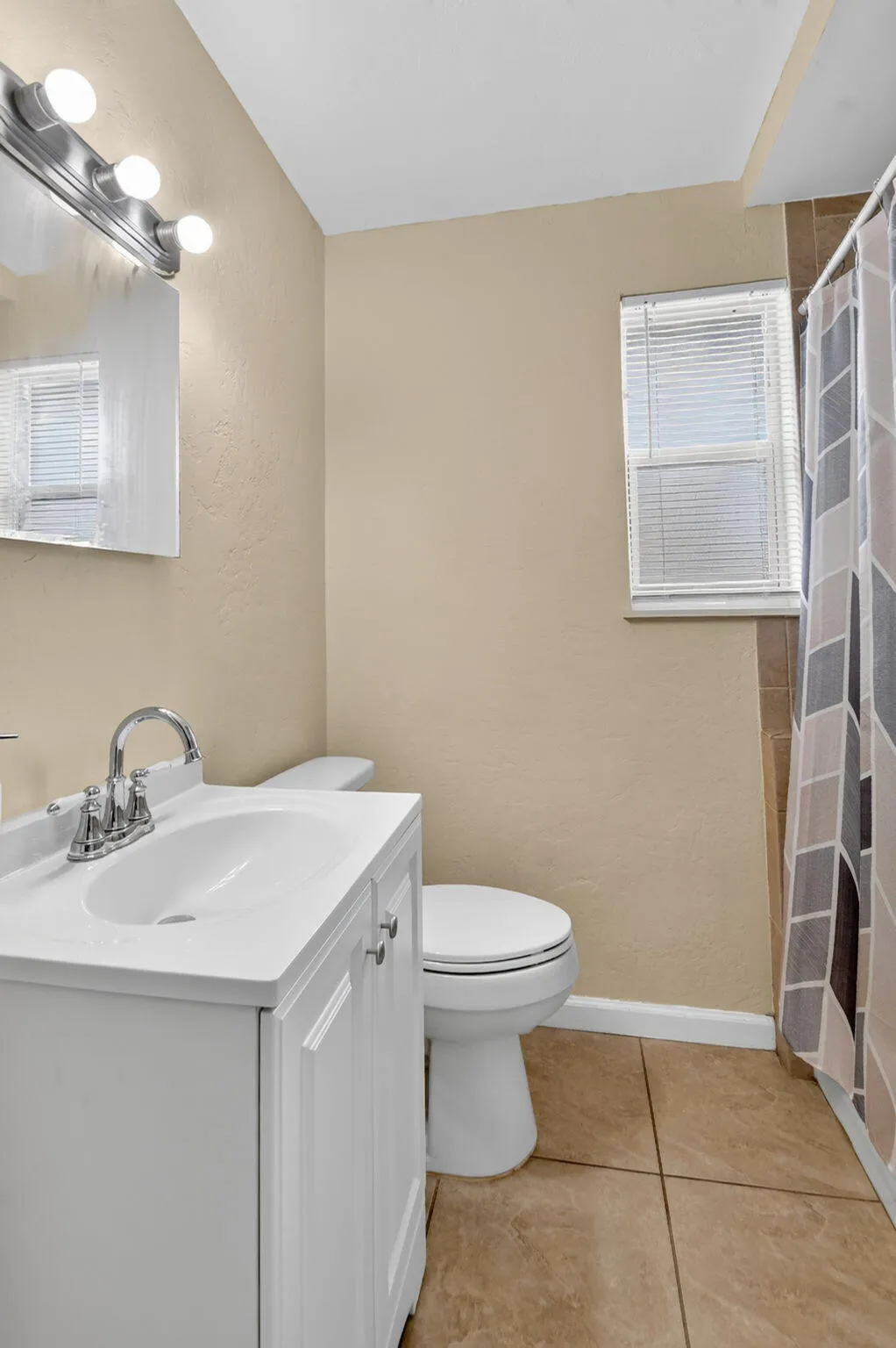 White vanity with integrated sink, chrome faucet, and rectangular mirror