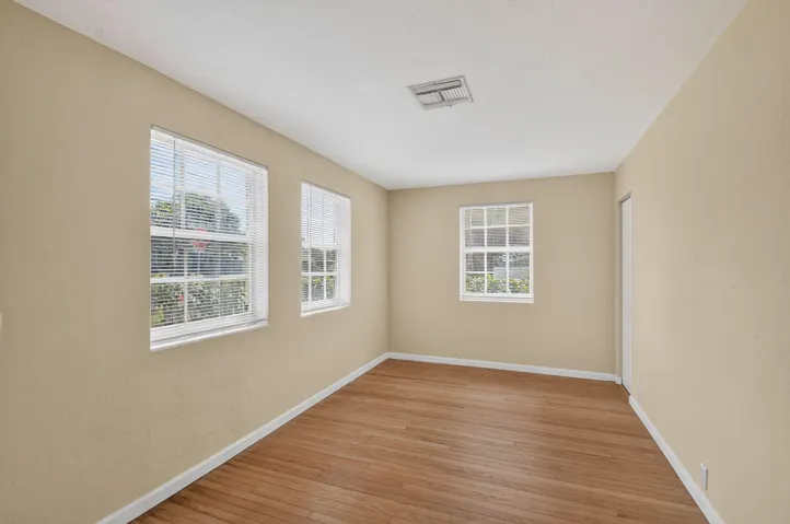 Wood-finish flooring with neutral wall tones, multiple windows, and overhead lighting