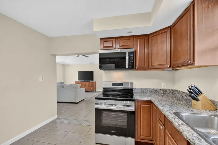 Kitchen featuring wood cabinetry, stainless steel appliances, a stainless steel sink, and stone-finish countertops