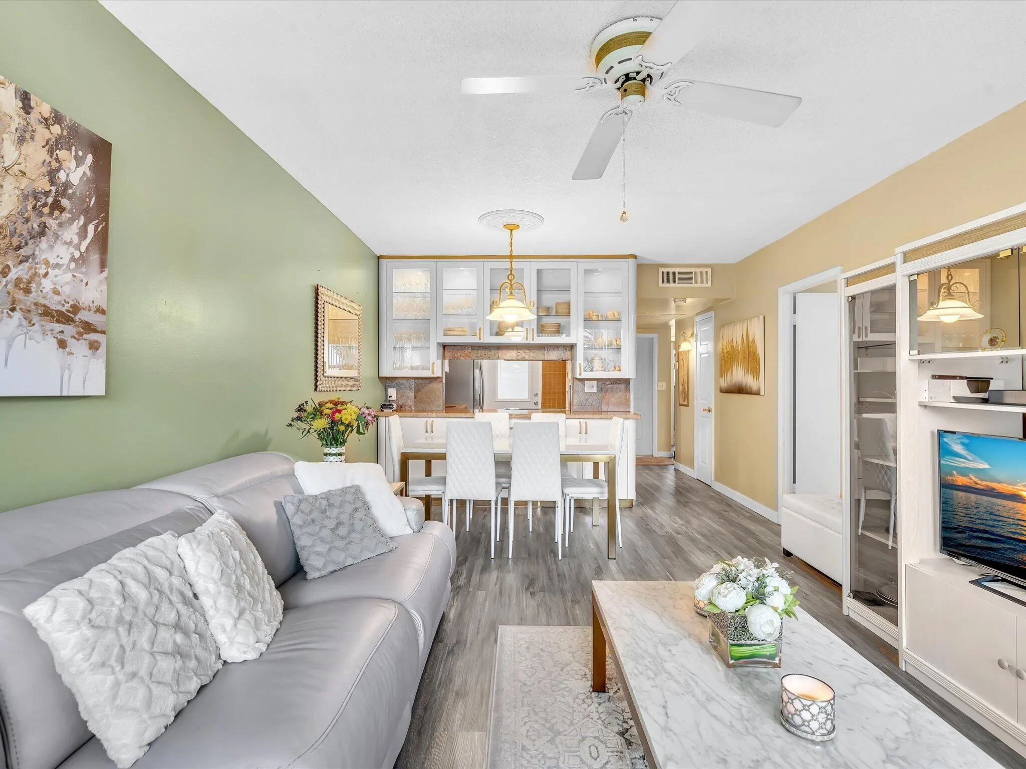 Wood-finish flooring throughout, a dining area with pendant lighting, a ceiling fan, and built-in cabinetry with glass panel doors