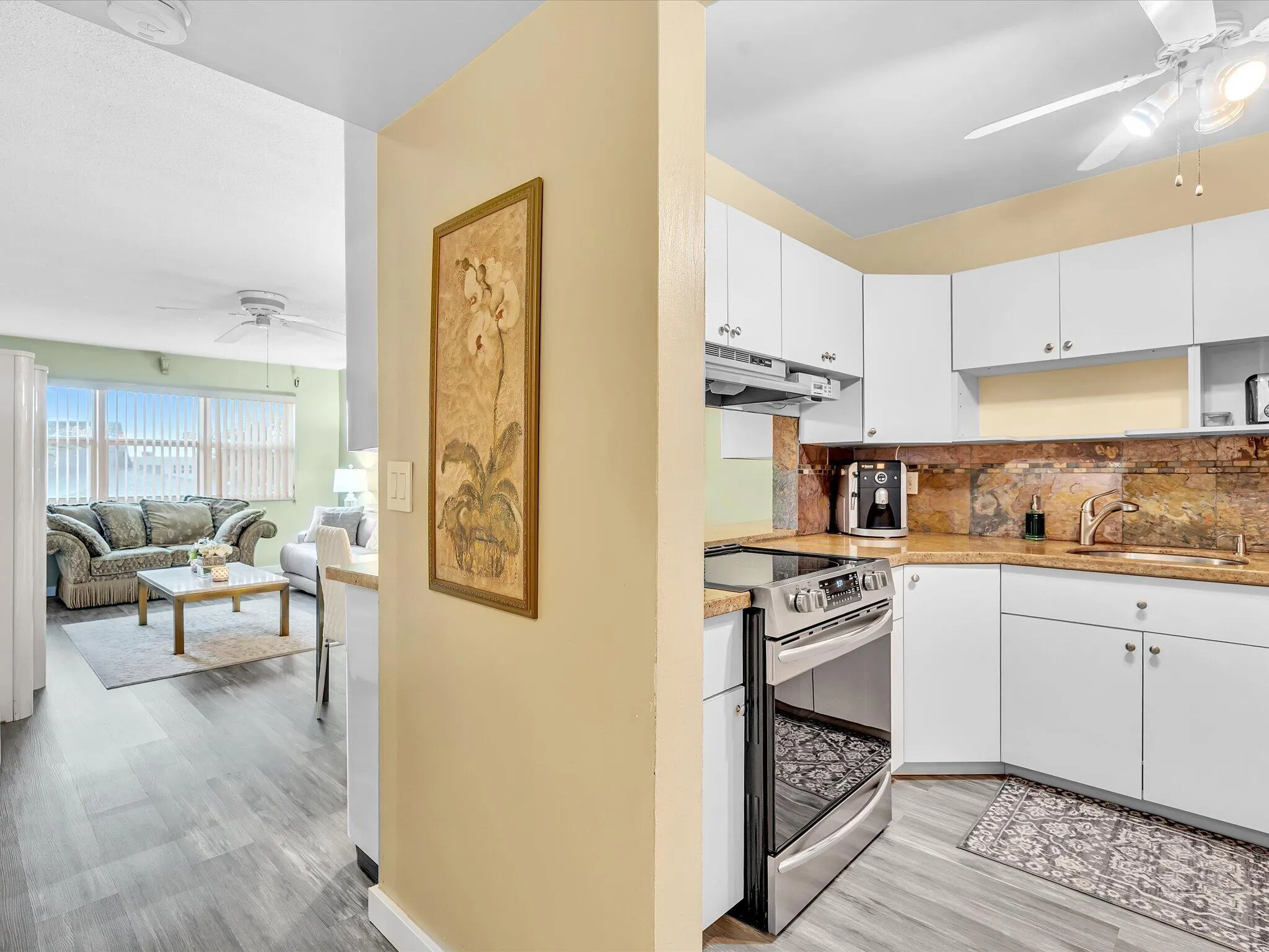 Kitchen featuring white cabinetry, stainless steel range, and stone countertops with matching backsplash