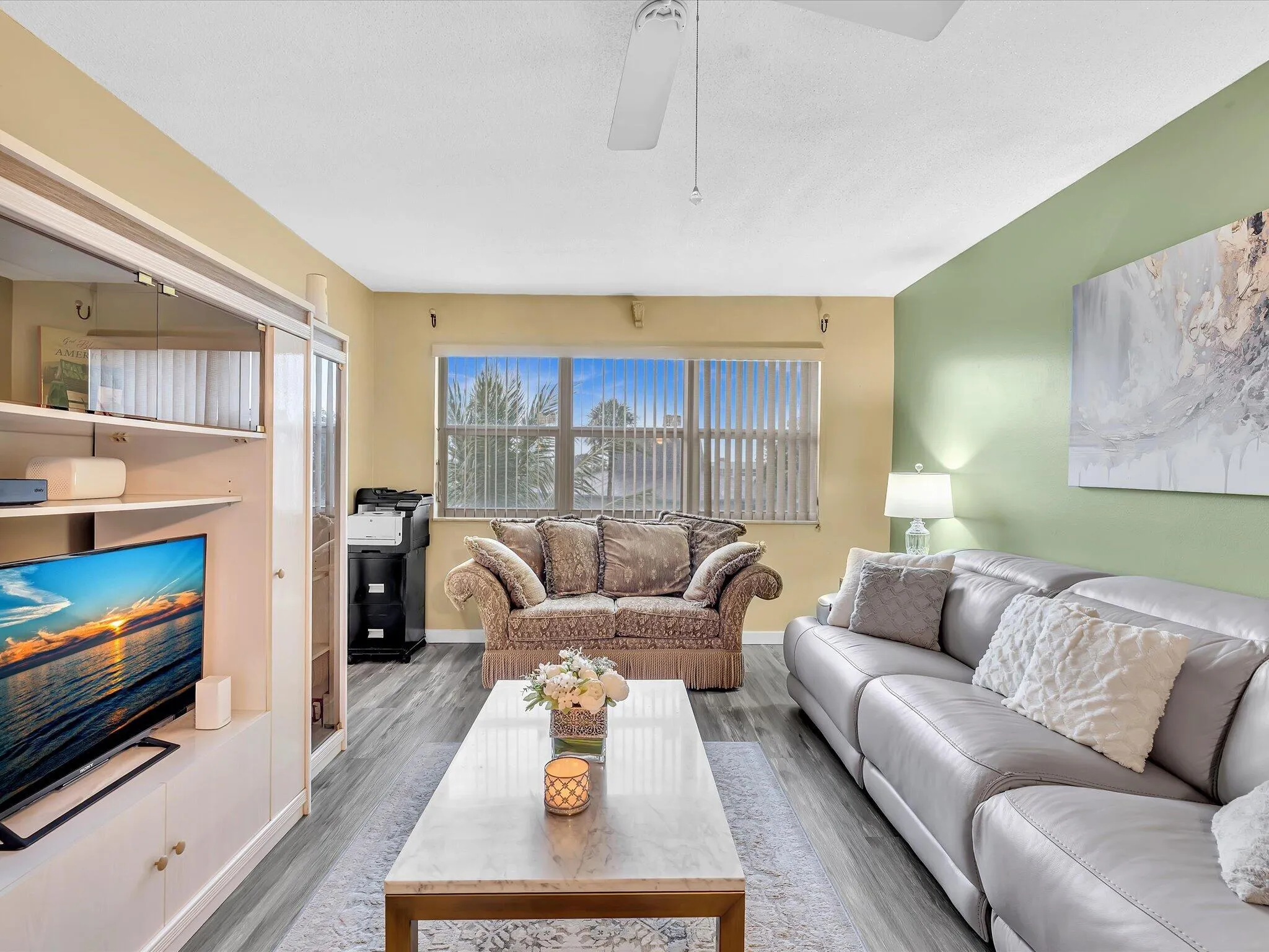 Recessed window with blinds, wood-finish flooring, ceiling fan, and built-in media cabinetry