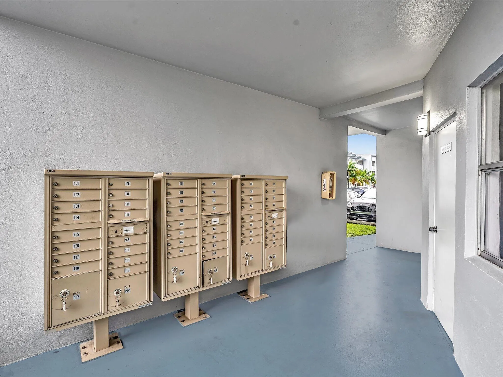 Wall-mounted mailboxes with individual locking compartments, exterior wall sconce, and solid entry door