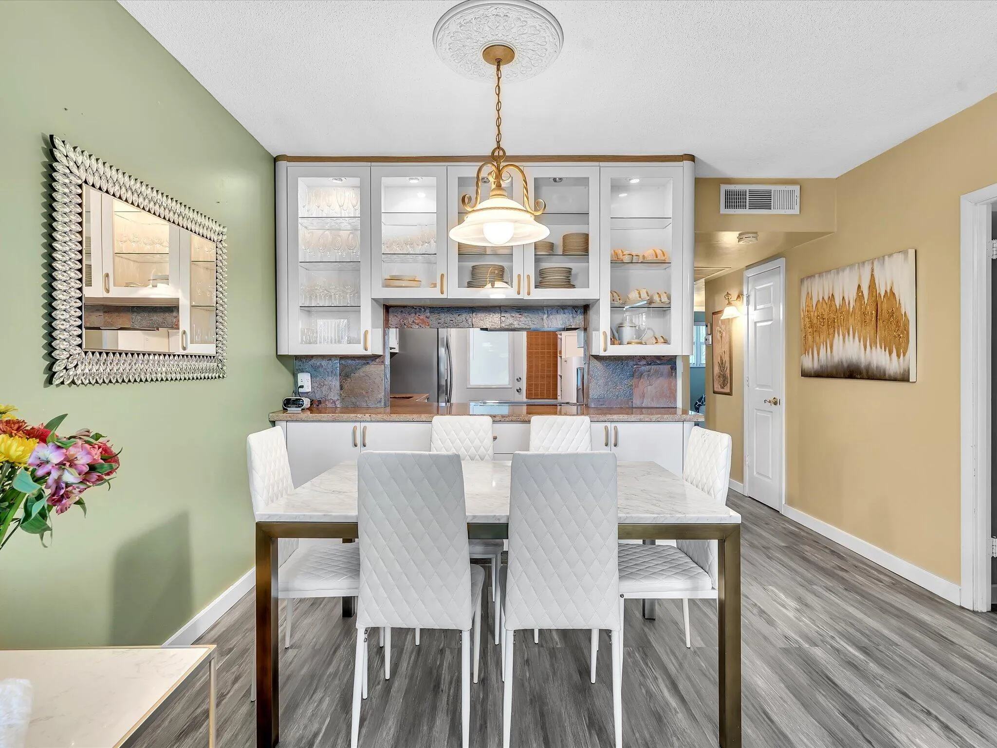 Dining area featuring wood-finish flooring, a decorative ceiling medallion, and a built-in buffet with glass-front cabinetry and stone-look backsplash