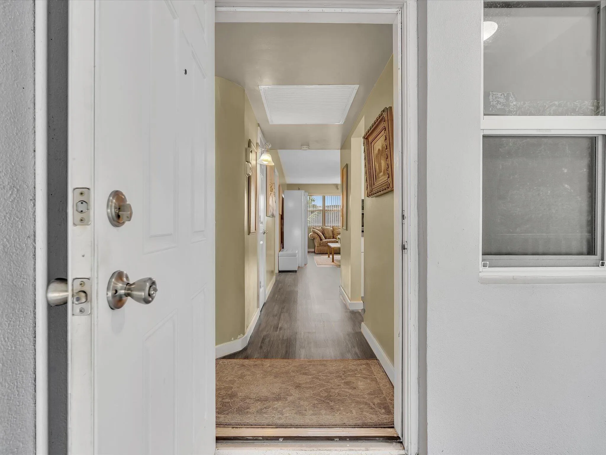 Inviting entry with a white paneled door, durable wood-finish flooring, and a sunlit interior