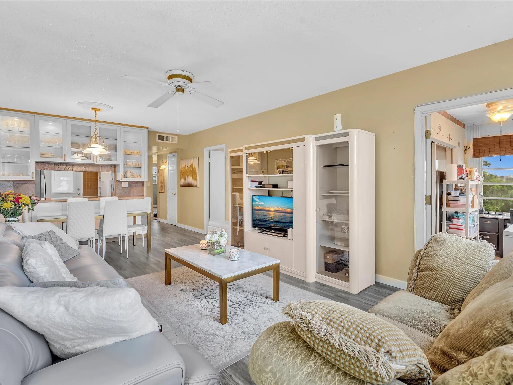 Recessed lighting, wood-finish flooring, white ceiling fan, built-in display cabinetry, and a dining area with pendant lighting