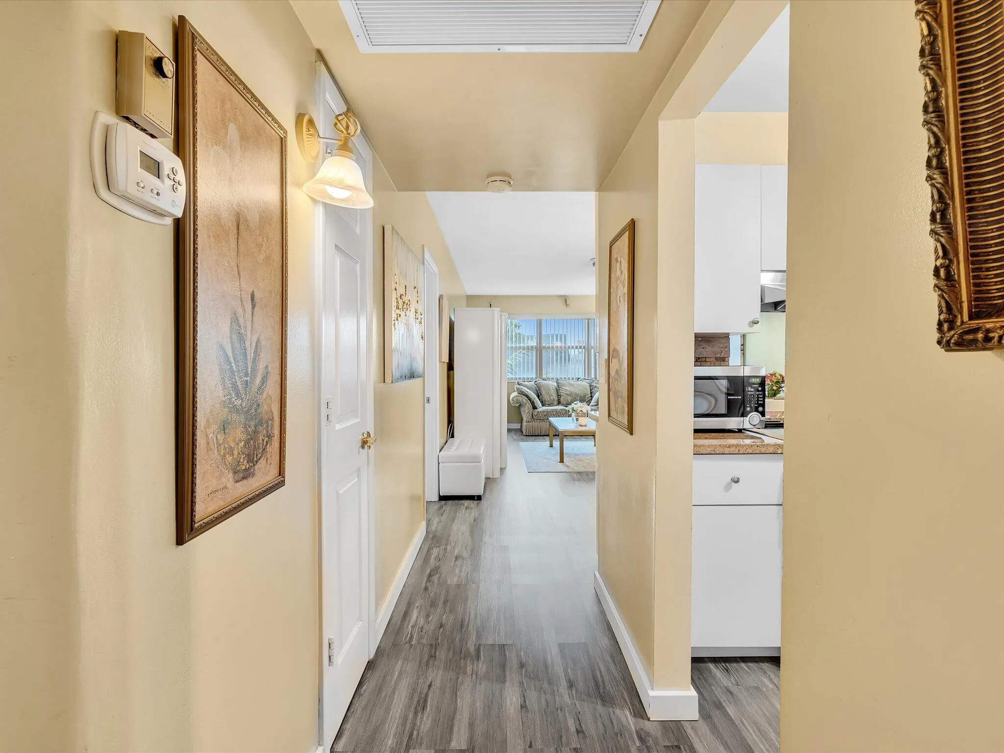 Hallway featuring wood-finish flooring, white doors, a wall sconce, and recessed lighting