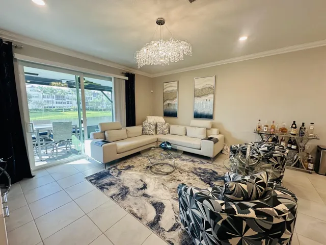 living room area with impact sliders opening to lanai with water view and fountain in back of the clubhouse steps​​‌​​​​‌​​‌‌​‌‌​​​‌‌​‌​‌​‌​​​‌​​ away