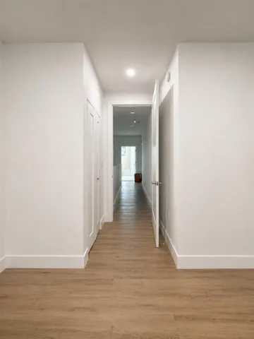 Hallway with wood-finish flooring, recessed lighting, and white paneled doors