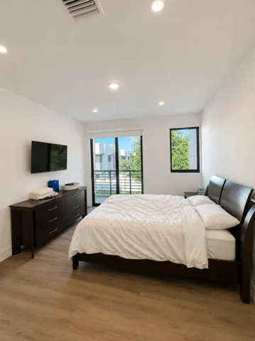 Wood-finish flooring, recessed ceiling lighting, and a sliding glass door leading to a private balcony
