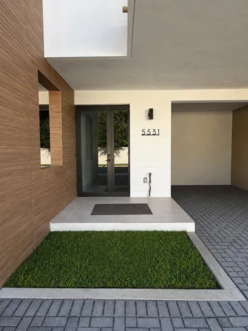 Modern entry with wood-panel siding, large format entry door, and integrated wall sconce