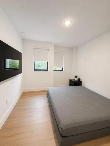 Recessed lighting, wood-finish flooring, two windows with roller shades, and a black built-in wall feature