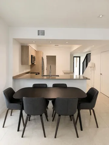 Kitchen pass-through with recessed lighting, stainless steel sink, wood-finish cabinetry, and light-toned countertops