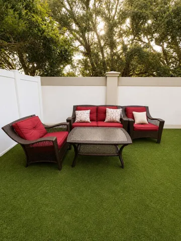 Expansive artificial turf area, privacy fencing, and a stucco wall with decorative pilasters