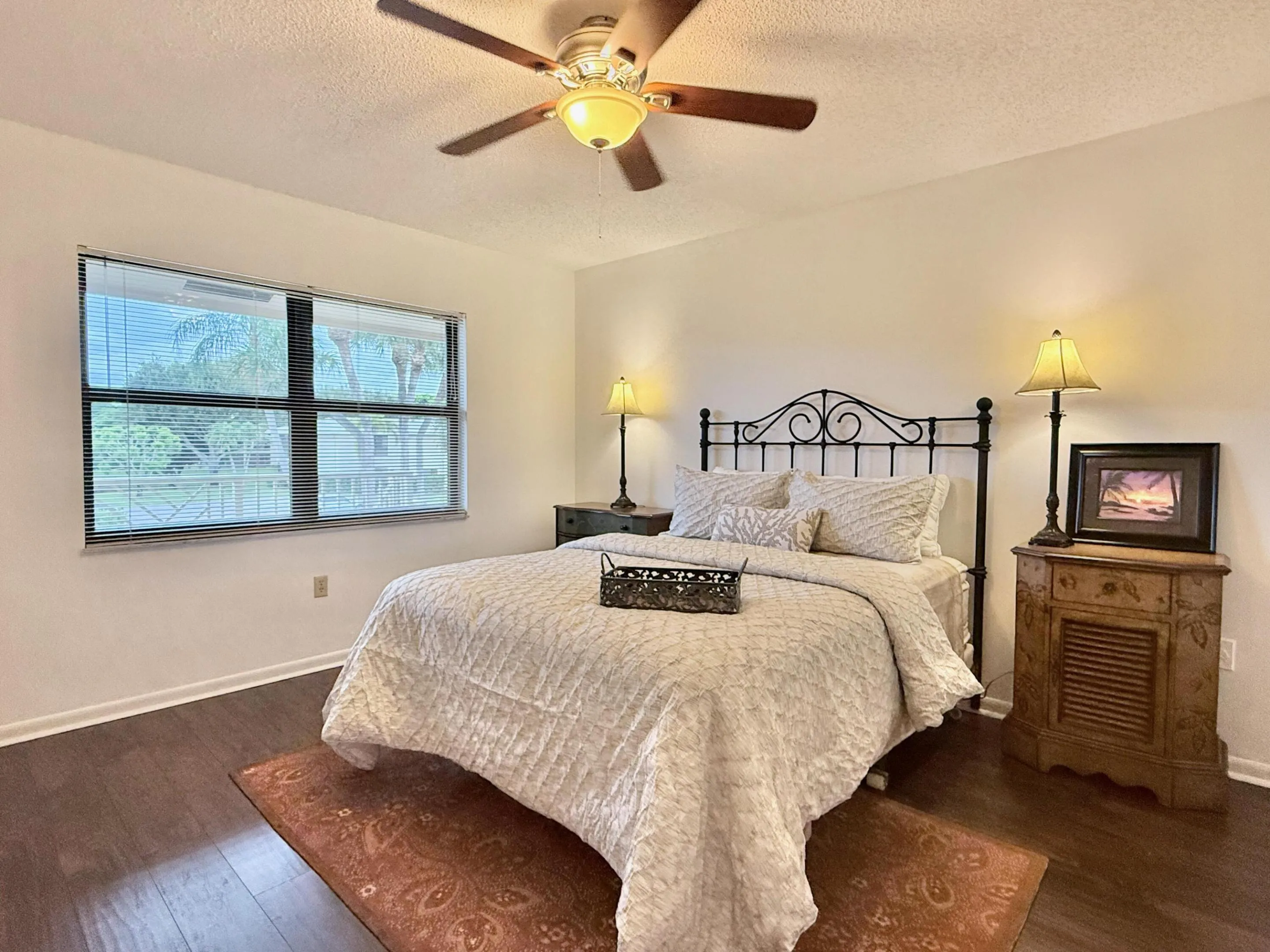 Wood-finish flooring, overhead ceiling fan with integrated lighting, window with blinds, and painted walls