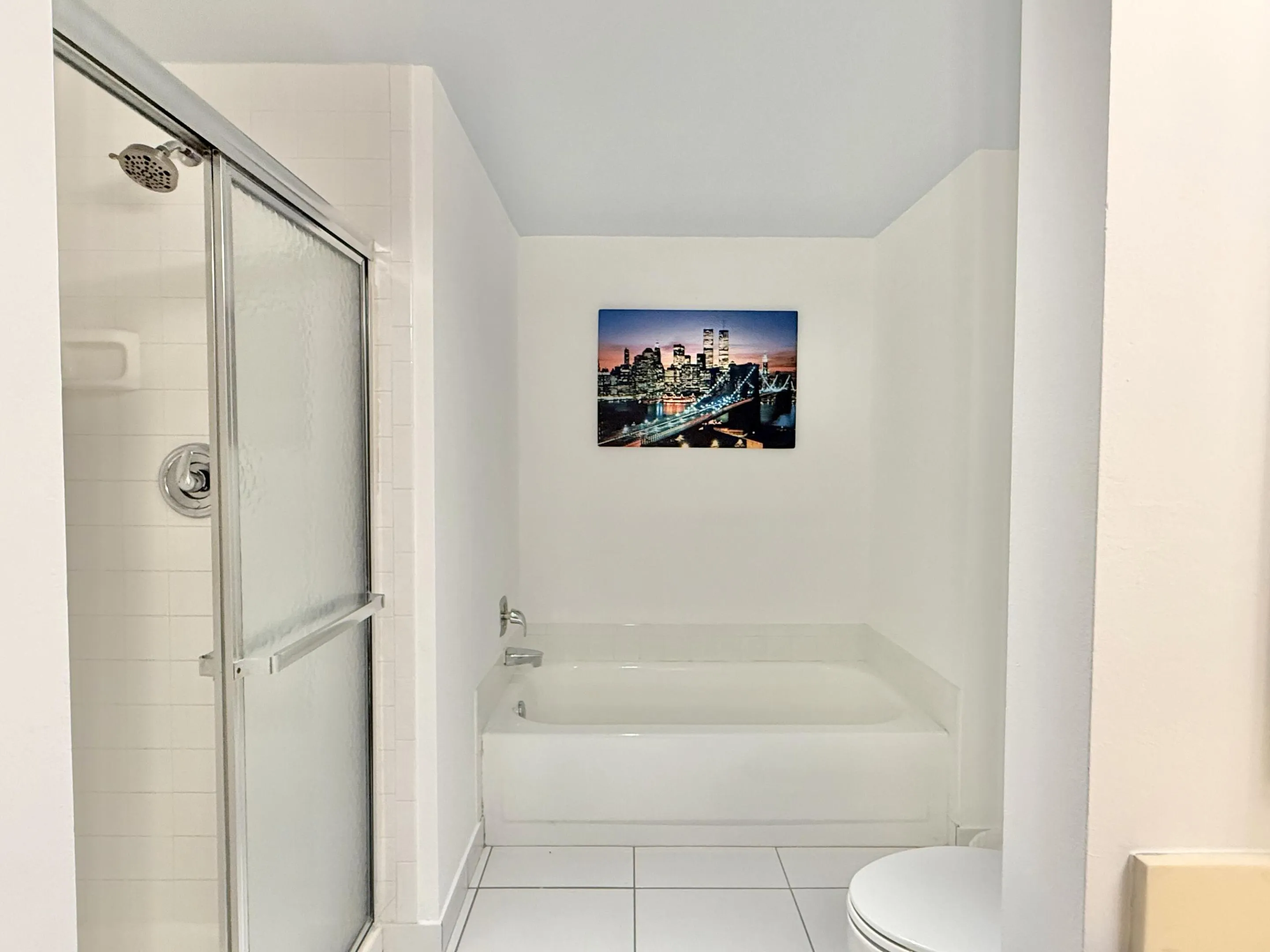 White tile flooring, built-in bathtub, and a separate shower with a clear glass enclosure