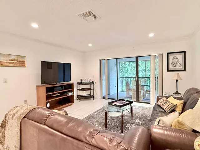 White tile flooring, recessed lighting, crown molding, and sliding glass doors opening to a balcony